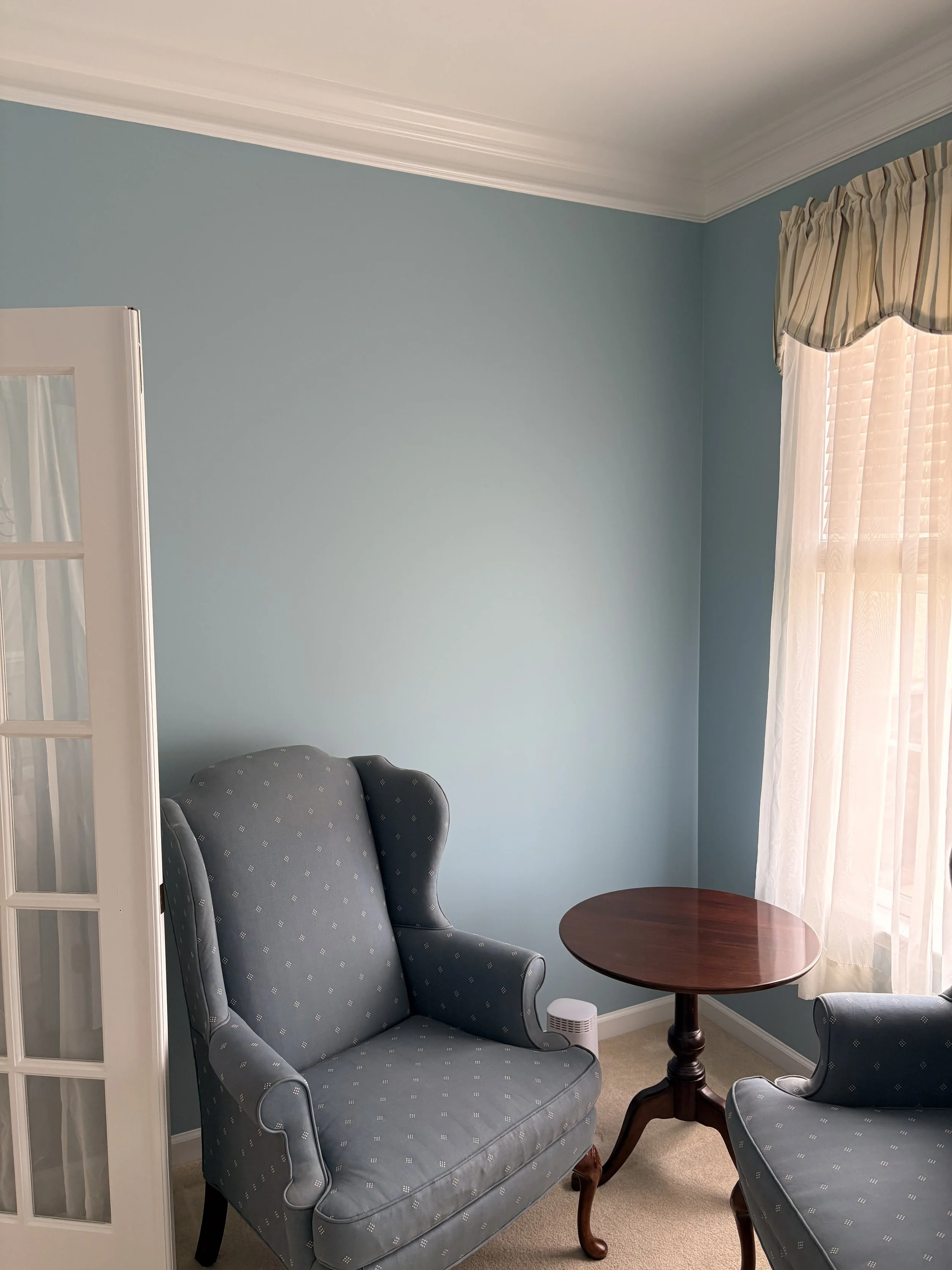 Sitting room with soft blue walls and white crown molding