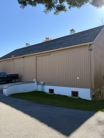 Finished whole-house exterior with tan vertical siding, white trim and white foundation